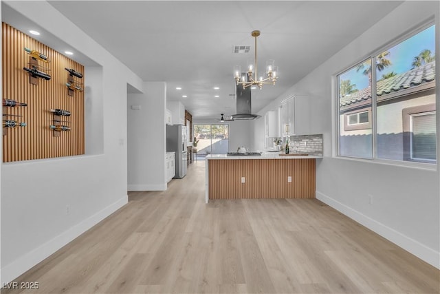 10200 Wood Work Ln, Las Vegas, NV 89135 - kitchen featuring freestanding refrigerator, a peninsula, island range hood, white cabinets, and a chandelier