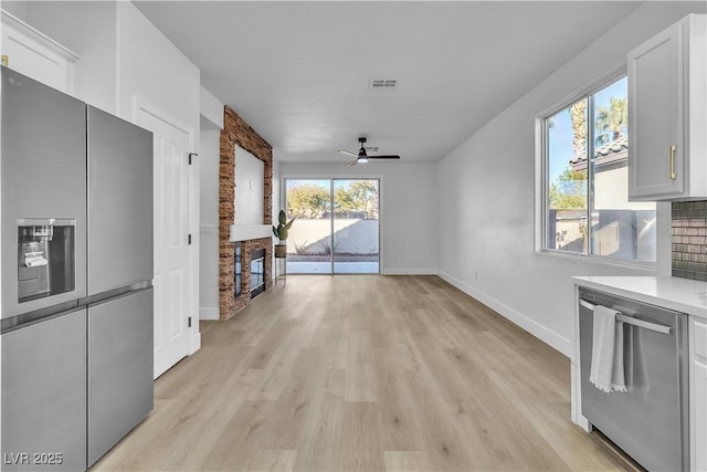10200 Wood Work Ln, Las Vegas, NV 89135 - kitchen with stainless steel appliances, ceiling fan, light wood-type flooring, white cabinets, and light countertops