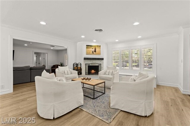3108 Sonia Dr, Las Vegas, NV 89107 - living area featuring ornamental molding, light wood-type flooring, a warm lit fireplace, and recessed lighting