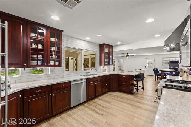 3108 Sonia Dr, Las Vegas, NV 89107 - kitchen featuring appliances with stainless steel finishes, a peninsula, decorative backsplash, light wood-type flooring, and recessed lighting