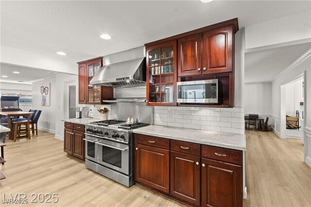 3108 Sonia Dr, Las Vegas, NV 89107 - kitchen featuring wall chimney exhaust hood, appliances with stainless steel finishes, tasteful backsplash, light wood-style floors, and recessed lighting