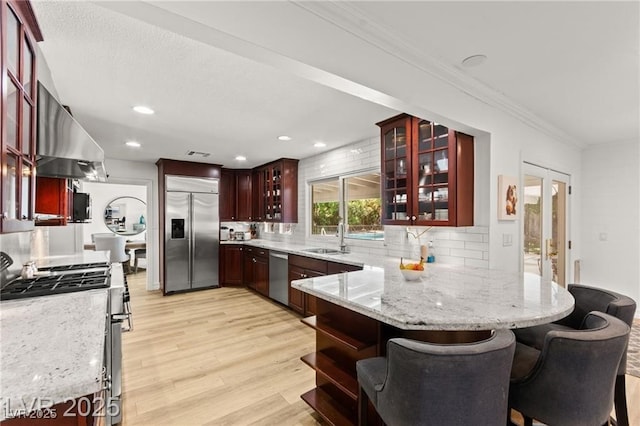 3108 Sonia Dr, Las Vegas, NV 89107 - kitchen with stainless steel appliances, a peninsula, light wood finished floors, tasteful backsplash, and crown molding