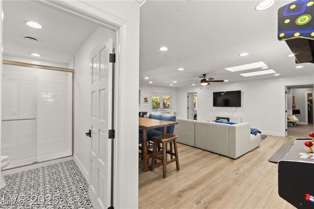3108 Sonia Dr, Las Vegas, NV 89107 - bathroom featuring a ceiling fan, recessed lighting, a stall shower, wood finished floors, and a skylight