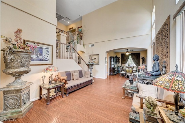 3873 Palm Island Ct, Las Vegas, NV 89147 - living room with arched walkways, wood finished floors, a high ceiling, stairs, and a ceiling fan