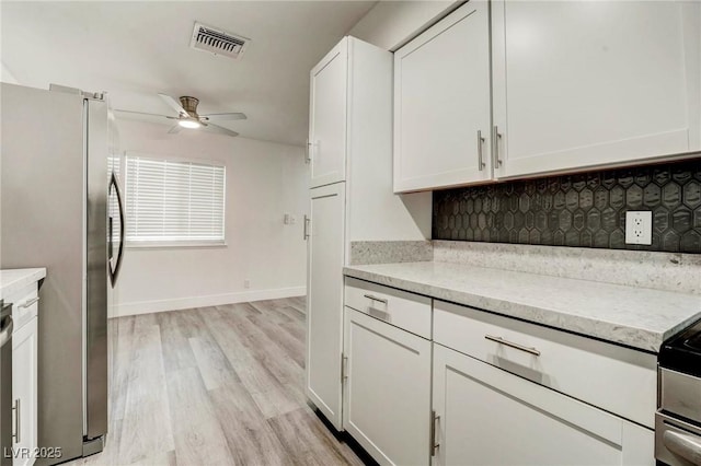 4432 Ash Ave, Las Vegas, NV 89110 - kitchen with freestanding refrigerator, a ceiling fan, white cabinets, light wood-style floors, and tasteful backsplash