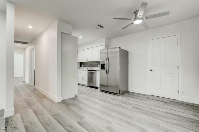4432 Ash Ave, Las Vegas, NV 89110 - kitchen with stainless steel appliances, white cabinets, light wood-style floors, a ceiling fan, and tasteful backsplash