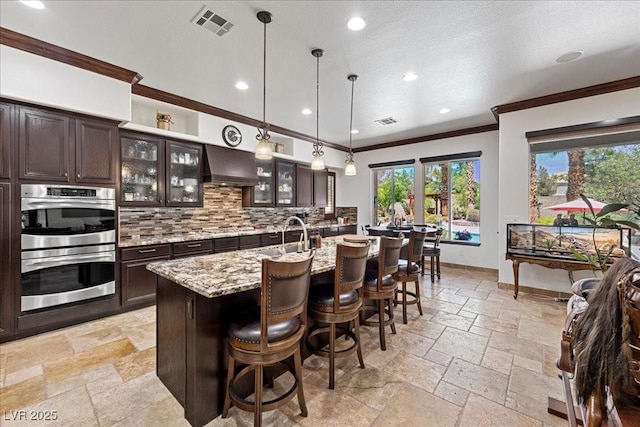 10674 Chillingham Dr, Las Vegas, NV 89183 - kitchen featuring custom range hood, ornamental molding, appliances with stainless steel finishes, healthy amount of natural light, and decorative backsplash