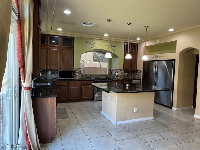 6277 Mustang Spring Ave, Las Vegas, NV 89139 - kitchen with stainless steel appliances, decorative backsplash, arched walkways, ornamental molding, and light tile patterned floors