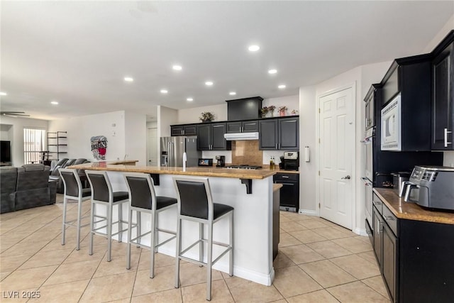 6351 Abacus Farms Ct, Las Vegas, NV 89131 - kitchen featuring appliances with stainless steel finishes, open floor plan, a kitchen bar, light tile patterned floors, and recessed lighting