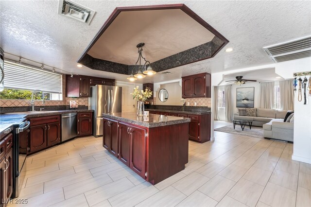 4530 W Shelbourne Ave, Las Vegas, NV 89139 - kitchen with stainless steel appliances, a textured ceiling, dark countertops, dark brown cabinets, and tasteful backsplash
