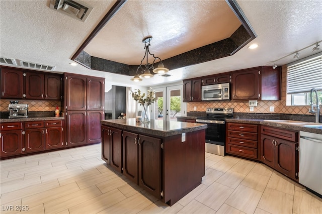 4530 W Shelbourne Ave, Las Vegas, NV 89139 - kitchen with stainless steel appliances, a textured ceiling, dark countertops, a kitchen island, and decorative backsplash