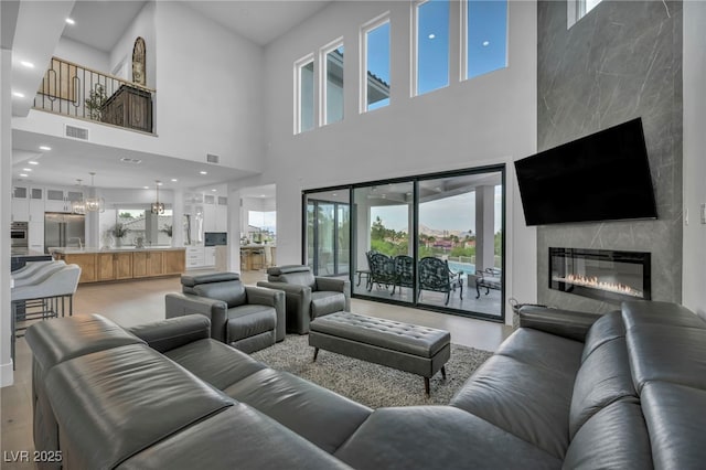 2058 Troon Dr, Henderson, NV 89074 - living area featuring a towering ceiling, a fireplace, healthy amount of natural light, a chandelier, and light wood-style floors