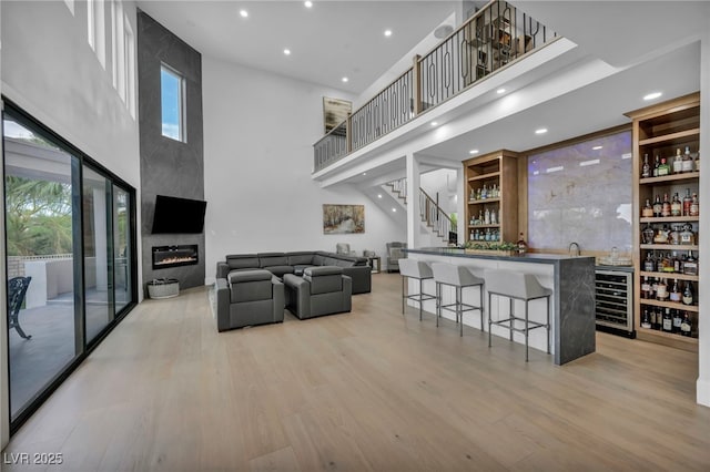 2058 Troon Dr, Henderson, NV 89074 - indoor wet bar with beverage cooler, a towering ceiling, light wood-style flooring, a fireplace, and stairway