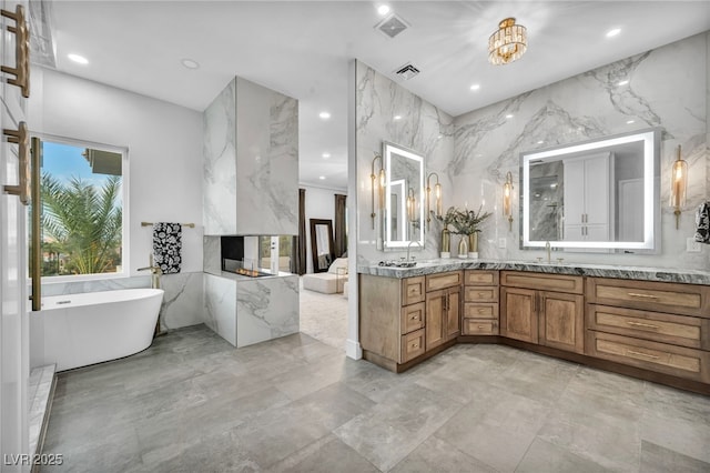 2058 Troon Dr, Henderson, NV 89074 - bathroom with double vanity, a freestanding bath, a fireplace, recessed lighting, and marble tiled flooring