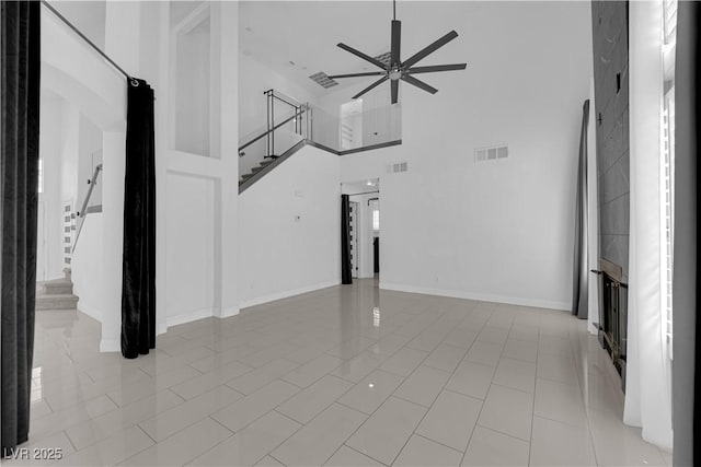 4604 Barnes Ct, Las Vegas, NV 89147 - unfurnished living room featuring a ceiling fan, a towering ceiling, stairs, light tile patterned floors, and arched walkways