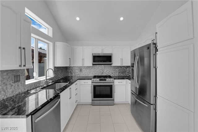 4604 Barnes Ct, Las Vegas, NV 89147 - kitchen featuring stainless steel appliances, vaulted ceiling, dark stone countertops, decorative backsplash, and white cabinets