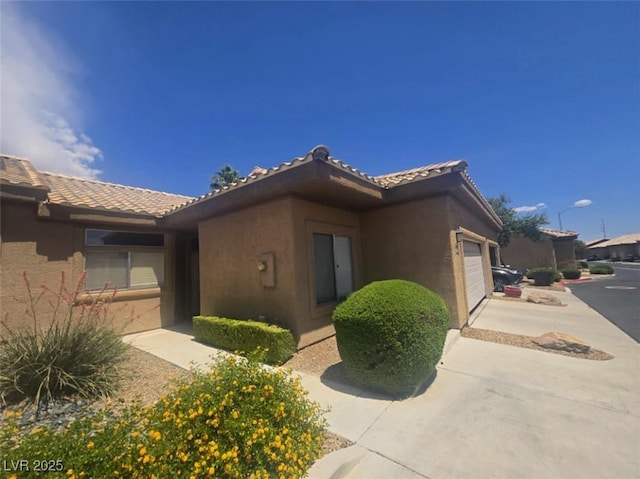 4764 Wild Draw Dr, North Las Vegas, NV 89031 - view of side of home featuring stucco siding, a garage, and a tiled roof
