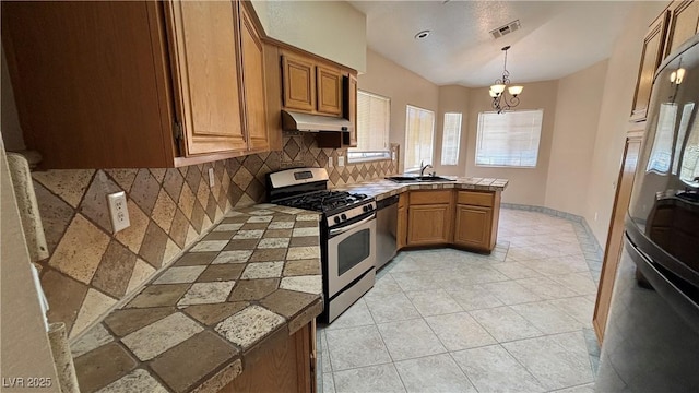 1081 Overture Dr, Las Vegas, NV 89123 - kitchen with stainless steel appliances, under cabinet range hood, a peninsula, tile counters, and tasteful backsplash