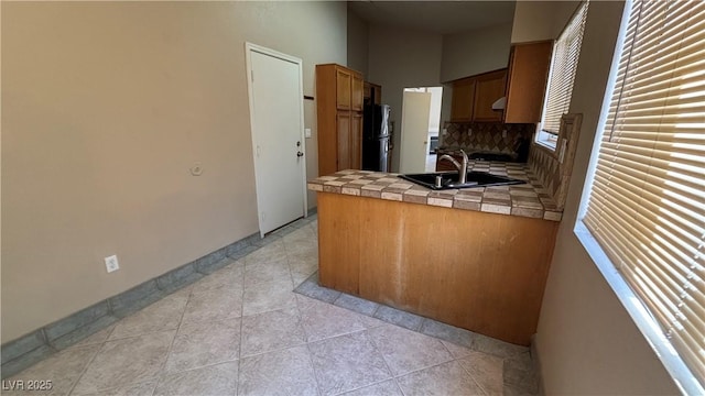 1081 Overture Dr, Las Vegas, NV 89123 - kitchen featuring tile countertops, a peninsula, freestanding refrigerator, tasteful backsplash, and exhaust hood