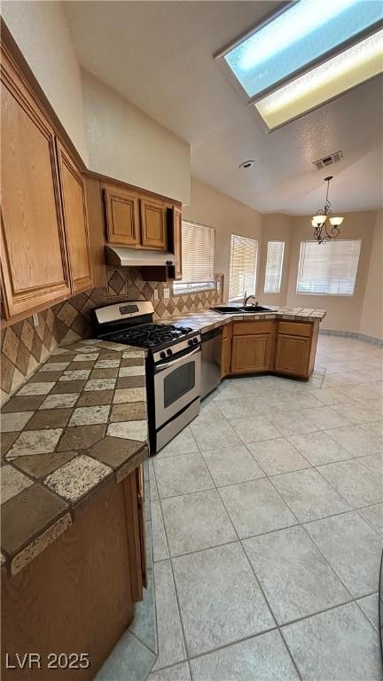 1081 Overture Dr, Las Vegas, NV 89123 - kitchen featuring stainless steel appliances, backsplash, brown cabinets, and a peninsula