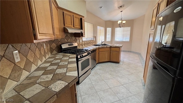1081 Overture Dr, Las Vegas, NV 89123 - kitchen with appliances with stainless steel finishes, a peninsula, decorative backsplash, under cabinet range hood, and tile countertops