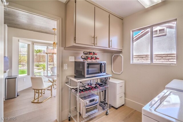 3101 Hayden Ct, Las Vegas, NV 89134 - kitchen featuring stainless steel microwave, light wood-style floors, separate washer and dryer, and light countertops