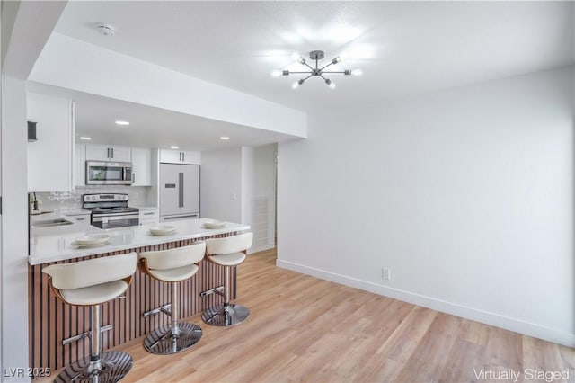 3459 One Nation Ave, Las Vegas, NV 89121 - kitchen featuring appliances with stainless steel finishes, a breakfast bar, a chandelier, light countertops, and white cabinets