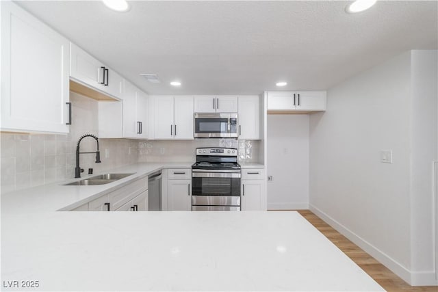 3459 One Nation Ave, Las Vegas, NV 89121 - kitchen with appliances with stainless steel finishes, light countertops, tasteful backsplash, white cabinetry, and light wood-type flooring