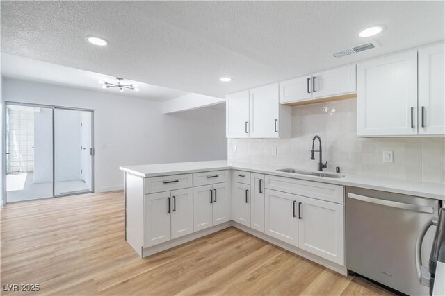 3459 One Nation Ave, Las Vegas, NV 89121 - kitchen with dishwasher, a peninsula, light countertops, light wood-style flooring, and a textured ceiling