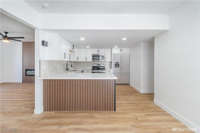 3459 One Nation Ave, Las Vegas, NV 89121 - kitchen featuring appliances with stainless steel finishes, a peninsula, a ceiling fan, light wood finished floors, and recessed lighting