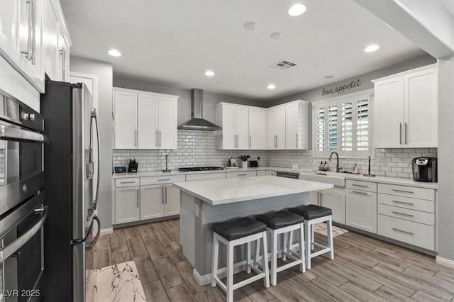 7456 Tinley Creek Ave, Las Vegas, NV 89113 - kitchen featuring wall chimney exhaust hood, stainless steel appliances, white cabinetry, wood finished floors, and recessed lighting