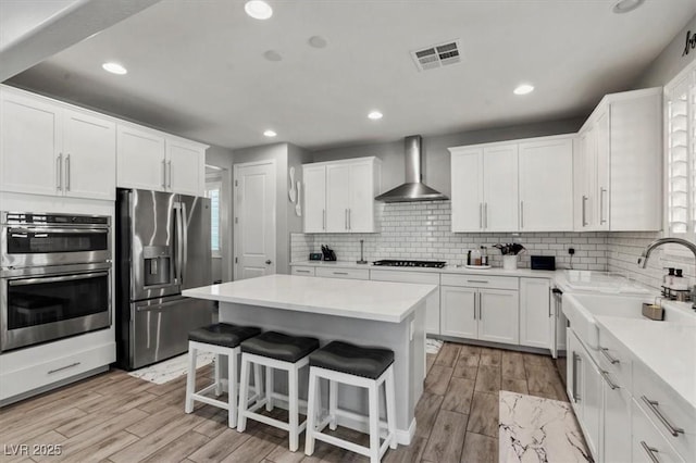 7456 Tinley Creek Ave, Las Vegas, NV 89113 - kitchen featuring appliances with stainless steel finishes, wall chimney range hood, a kitchen island, white cabinets, and recessed lighting