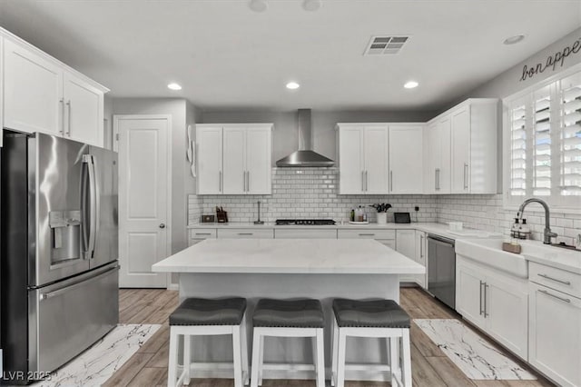 7456 Tinley Creek Ave, Las Vegas, NV 89113 - kitchen featuring stainless steel appliances, wall chimney exhaust hood, white cabinetry, a kitchen bar, and recessed lighting