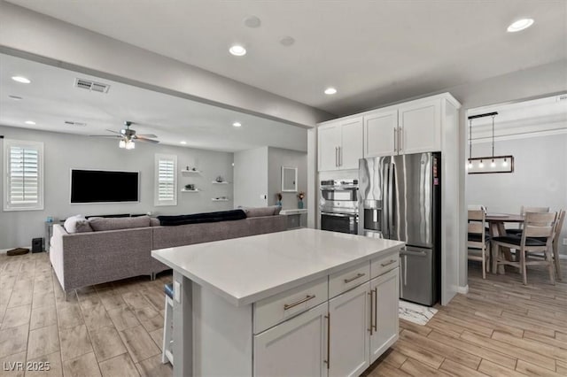 7456 Tinley Creek Ave, Las Vegas, NV 89113 - kitchen featuring appliances with stainless steel finishes, white cabinetry, a kitchen island, a ceiling fan, and light wood-type flooring