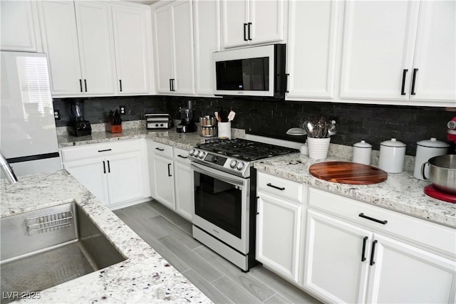 8131 Skye Plum St, Las Vegas, NV 89166 - kitchen with white microwave, stainless steel gas stove, white cabinets, and backsplash