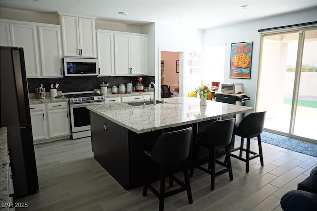 8131 Skye Plum St, Las Vegas, NV 89166 - kitchen with appliances with stainless steel finishes, wood finished floors, decorative backsplash, white cabinets, and recessed lighting