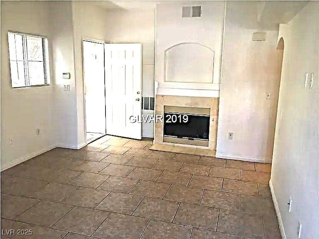 8417 Running Deer Ave Unit 101, Las Vegas, NV 89145 - unfurnished living room featuring a tiled fireplace and arched walkways