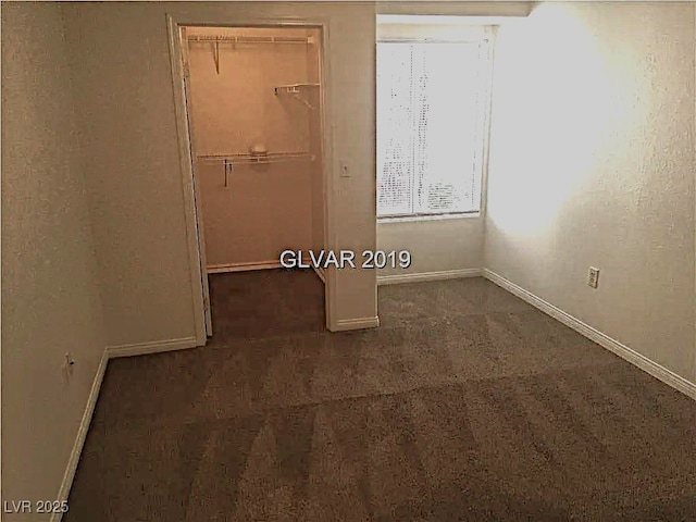 8417 Running Deer Ave Unit 101, Las Vegas, NV 89145 - unfurnished bedroom featuring dark colored carpet, a closet, and a walk in closet