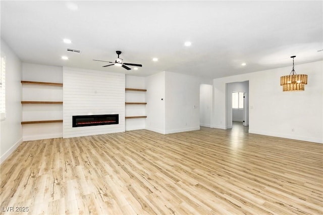 10302 Artful Stone Ave, Las Vegas, NV 89149 - unfurnished living room with recessed lighting, a large fireplace, light wood-style flooring, ceiling fan, and a chandelier