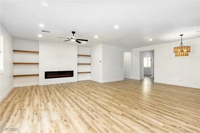 10302 Artful Stone Ave, Las Vegas, NV 89149 - unfurnished living room with recessed lighting, a large fireplace, light wood-style flooring, ceiling fan, and a chandelier
