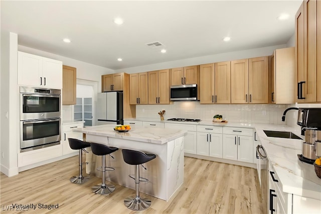 10302 Artful Stone Ave, Las Vegas, NV 89149 - kitchen with appliances with stainless steel finishes, light wood finished floors, light stone counters, a breakfast bar, and recessed lighting