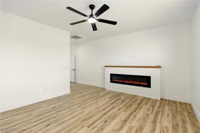 10302 Artful Stone Ave, Las Vegas, NV 89149 - unfurnished living room featuring a glass covered fireplace, light wood-type flooring, and a ceiling fan