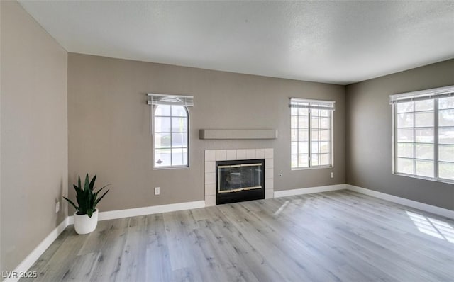 507 Satin Saddle Pl, Henderson, NV 89052 - unfurnished living room featuring healthy amount of natural light, wood finished floors, a tile fireplace, and a textured ceiling