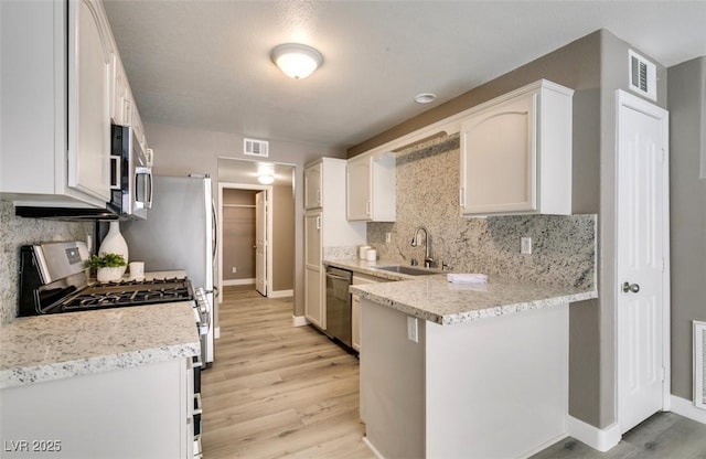 507 Satin Saddle Pl, Henderson, NV 89052 - kitchen with stainless steel appliances, light wood-style floors, white cabinets, and backsplash