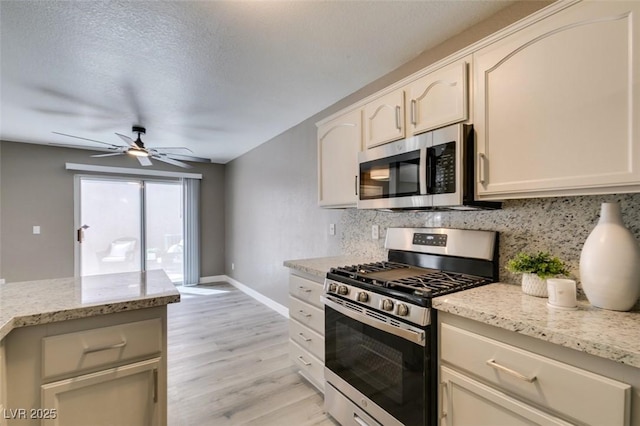 507 Satin Saddle Pl, Henderson, NV 89052 - kitchen with appliances with stainless steel finishes, a ceiling fan, tasteful backsplash, light wood finished floors, and light stone countertops