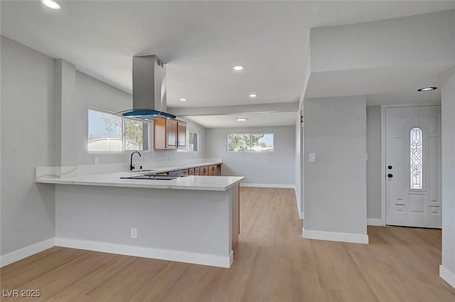 4807 Sacks Dr, Las Vegas, NV 89122 - kitchen with island range hood, light countertops, light wood-style flooring, a peninsula, and recessed lighting