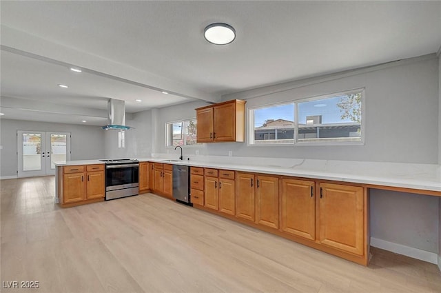 4807 Sacks Dr, Las Vegas, NV 89122 - kitchen featuring appliances with stainless steel finishes, island exhaust hood, french doors, light wood finished floors, and light countertops
