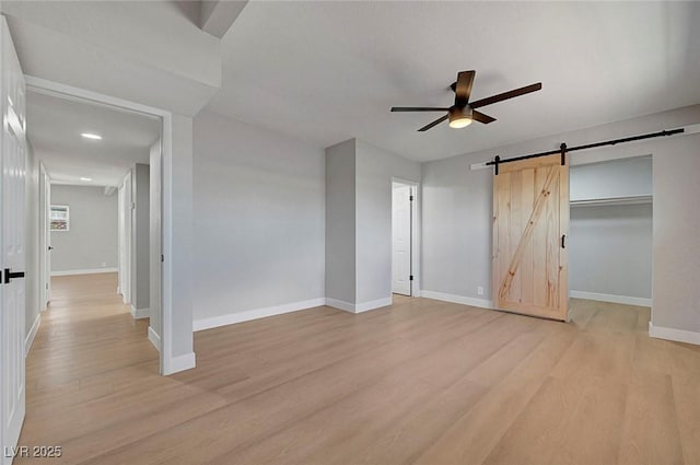 4807 Sacks Dr, Las Vegas, NV 89122 - unfurnished bedroom with light wood finished floors, a barn door, a ceiling fan, and a walk in closet