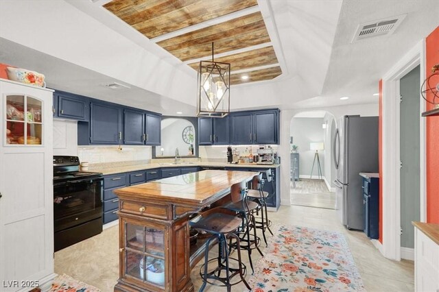 5008 Donnie Ave, Las Vegas, NV 89130 - kitchen featuring black electric range, freestanding refrigerator, arched walkways, light countertops, and light tile patterned floors