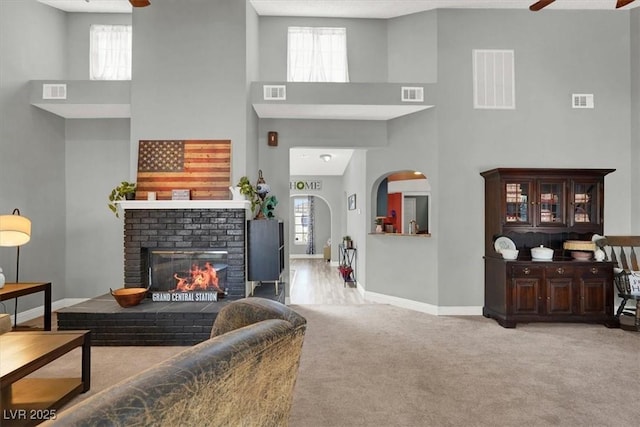 5008 Donnie Ave, Las Vegas, NV 89130 - carpeted living area featuring ceiling fan, a towering ceiling, healthy amount of natural light, a brick fireplace, and arched walkways
